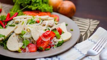 würzig Glas Nudel Salat mit Vietnamesisch Würstchen serviert im ein grau Teller stellen auf ein hölzern Tabelle und verschiedene Gemüse. foto