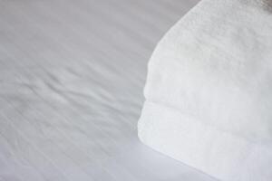 selektiv Fokus auf Weiß frisch Handtücher im Hotel Bett. Zimmer Bedienung Konzept. Nahansicht Weiß auf Neu Bettwäsche und persönlich Hygiene Artikel. foto