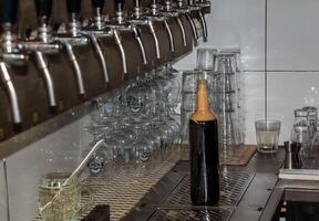 hinter das Schalter. Damen Hände schön und leicht gießen Bier in ein Flasche. foto