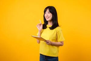 jung asiatisch Frau tragen Gelb T-Shirt und Jeans zeigen glücklich Lächeln während mit Digital Tablette, Anzeigen nachdenklich Ausdruck und kreativ Idee. Bildung Technologie innovativ Denken Konzept. foto
