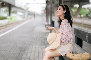 jung asiatisch Frau Reisender mit Weberei Korb warten zum Zug im Zug Bahnhof. Reise Ausflug Lebensstil, Welt Reise Forscher oder Asien Sommer- Tourismus Konzept. foto