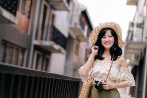 glücklich Jugend asiatisch Frau mit Kamera Reisen Straße Stadt Ausflug auf Freizeit Wochenende. jung Hipster weiblich Tourist Besichtigung Sommer- städtisch Bangkok Ziel. Asien Sommer- Tourismus Konzept. foto