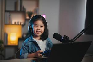 asiatisch Influencer jung Mädchen Lächeln heiter mit Joystick spielen Spiel Leben Streaming Gruß Video Konferenz mit Laptop und tragen Kopfhörer. Kinder Streaming Besetzung Spiel online Konzept. foto
