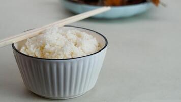 Weiß Reis im ein Schüssel und gebraten Fisch auf ein Weiß Teller sind serviert auf das Tabelle foto