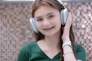 Porträt von Teenager Mädchen Hören zu Musik- mit Kopfhörer und Handy, Mobiltelefon Telefon. foto