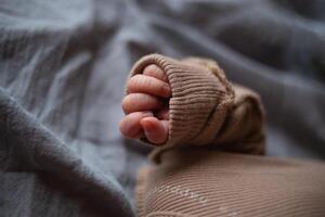 Nahansicht Schuss. das Neugeborene Babys klein Hand ist gefaltet in ein Faust auf ein grau Hintergrund foto