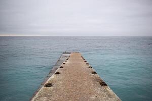 ein Seebrücke Das spaltet sich in zwei beim das Ende und geht aus zu Meer. foto