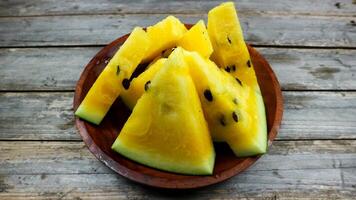 Gelb Wassermelone Scheiben auf hölzern Teller und isoliert auf grau Tafel Hintergrund. gesund Essen, vegan. Antioxidans foto