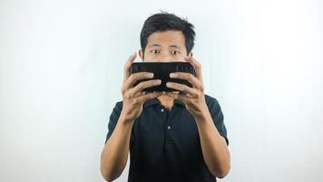 asiatisch Mann mit ein ernst Ausdruck ist spielen ein Spiel auf seine Zelle Telefon. foto