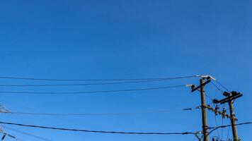 elektrisch Drähte und elektrisch Stangen Kreuzung das hoch Stromspannung Pole Turm gegen das Blau Himmel Hintergrund. foto