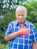 Senior Mann haben ein Herz Attacke. Alten asiatisch Mann umklammern seine Truhe im Schmerzen beim das zuerst Zeichen von . Konzept von alt Menschen und Gesundheitswesen foto