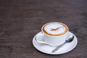 Tasse von Kaffee Cappuccino und Löffel auf hölzern Tabelle foto