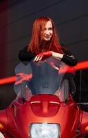 ein Frau Sitzung auf ein rot Motorrad. ein Frau Sitzung auf oben von ein rot Motorrad foto
