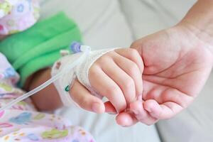 Mutter halten Kind Hand mit Kochsalzlösung iv Lösung im Krankenhaus foto