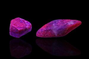 Makro Mineral Stein Rubin unter ultraviolett Licht auf ein schwarz Hintergrund foto