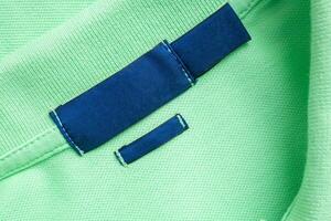 leer Blau Wäsche Pflege Kleider Etikette auf Grün Hemd Stoff Textur Hintergrund foto