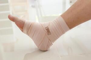 Mann mit Knöchel Verstauchung elastisch Binde zum Knöchel Verletzung und Gefühl Schmerzen foto