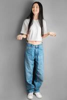 voll Länge Porträt von ein jung Mädchen im ein Weiß T-Shirt und Jeans. foto