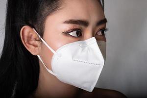 Nahaufnahme einer Frau, die eine Atemschutzmaske n95 aufsetzt, um sich vor durch die Luft übertragenen Atemwegserkrankungen wie dem Grippevirus Covid-19 Coronavirus Ebola pm2.5 Staub und Smog zu schützen foto