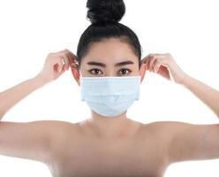 schöne junge asiatische frau, die eine medizinische maske aufsetzt, um vor atemwegserkrankungen wie der grippe covid-19 pm2.5 staub und smog zu schützen, frauensicherheitsvirusinfektionskonzept, kamera schauen foto