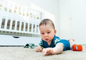 Baby beschäftigt, verlobt im Spielzeit auf das Boden. ein Baby Verlegung auf das Fußboden spielen mit ein Spielzeug foto