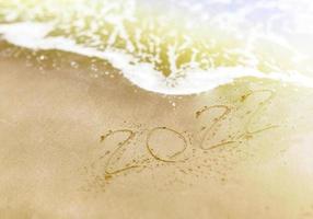 Frohes neues Jahr, Schriftzug Zahlen 2022 Jahr auf dem Sand foto