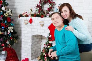Ehepaar mittleren Alters im Weihnachtszimmer, Kamin und Weihnachtsbaum des neuen Jahres, liebevolle Familie?