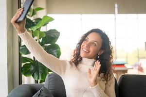 Latin Frau Videokonferenz auf Tablet mit glücklichem Gefühl foto