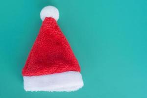 rot-weiße flauschige Weihnachtsmütze auf türkisfarbenem Hintergrund. Weihnachten und Neujahr Konzept. foto