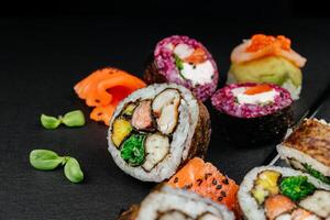 Sushi einstellen mit Kaviar, Avocado und Lachs. Sushi Stücke platziert zwischen Essstäbchen, getrennt auf schwarz Hintergrund. asiatisch Küche. oben Sicht. kostenlos Raum zum Ihre Text. hoch Qualität Foto