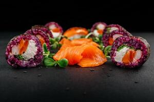 Sushi einstellen mit Kaviar, Avocado und Lachs. Sushi Stücke platziert zwischen Essstäbchen, getrennt auf schwarz Hintergrund. asiatisch Küche. oben Sicht. kostenlos Raum zum Ihre Text. hoch Qualität Foto
