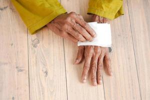 Ältere Frauen, die seine Hände mit einem feuchten Tuch desinfizieren. foto