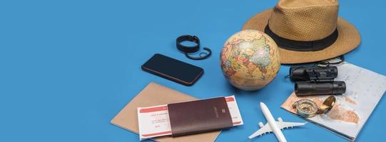touristische Planung des Urlaubs mit Hilfe der Weltkarte mit anderem Reisezubehör. Smartphone, Filmkamera und Sonnenbrille auf blauem Hintergrund. foto