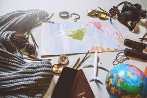 touristische Planung des Urlaubs mit Hilfe der Weltkarte mit anderem Reisezubehör. Smartphone, Filmkamera und Sonnenbrille auf weißem Hintergrund. Reiserucksack foto