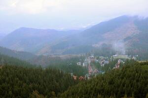 Morgen Aussicht von wohnhaft Bereich und Häuser um das Dragobrat Berg Spitzen im Karpaten Berge, Ukraine. wolkig und nebelig Landschaft um Drahobrat Spitzen foto