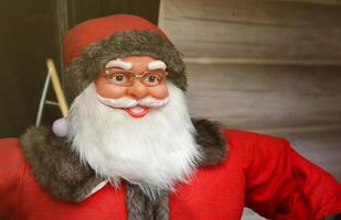 Santa claus groß Plastik Zahl mit klassisch Santa Kleider schließen zu hölzern Haus foto