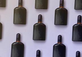 dunkelviolette Parfümflasche mit goldenem Band auf pastellfarbenem Papierhintergrund. trendiger Duft foto