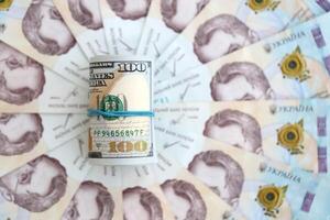 Bündel von hundert uns Dollar Rechnungen Lügen auf viele Banknoten von ukrainisch Griwna. wirtschaftlich Standard, Krise und Abwertung von ukrainisch National Währung foto