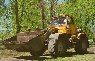 das stadtverbesserungsteam entfernt mit einem bagger und einem lkw das laub im park. regelmäßige saisonale Arbeiten zur Verbesserung der öffentlichen Erholungsorte foto