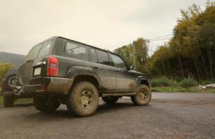 Automobil im ein Landschaft Landschaft mit ein Schlamm Straße. Offroad 4x4 suv Automobil mit ditry Körper nach Fahrt im schlammig Straße foto