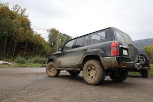 Automobil im ein Landschaft Landschaft mit ein Schlamm Straße. Offroad 4x4 suv Automobil mit ditry Körper nach Fahrt im schlammig Straße foto