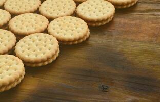 Ein runder Sandwichkeks mit Kokosfüllung liegt in großen Mengen auf einer braunen Holzoberfläche. Foto von essbaren Leckereien auf einem hölzernen Hintergrund mit Kopierraum