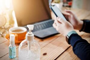 Frauen mit Laptop Arbeiten und sauber Hände mit Alkohol trinken Kaffee Tasse heiß beim Zuhause foto