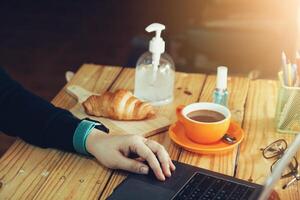 Frauen mit Laptop Arbeiten und sauber Hände mit Alkohol trinken Kaffee Tasse heiß beim Zuhause foto