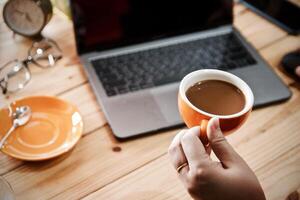 Frauen mit Laptop Arbeiten und sauber Hände mit Alkohol trinken Kaffee Tasse heiß beim Zuhause foto