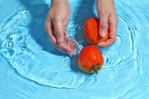 Frau Hand waschen Tomate in Wasser. Gemüse vor dem Kochen waschen foto