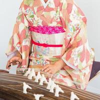 Unerkennbare Frau, die einen Kimono trägt und eine Koto spielt, ein traditionelles japanisches Saiteninstrument. foto
