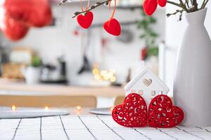 Schlüssel zu winzig Haus von gemütlich Zuhause mit Valentinstag Dekor auf Tabelle von Küche. Geschenk zum Valentinsgrüße Tag, Familie Liebe Nest. Design, Projekt, ziehen um zu Neu Haus, Hypothek, Miete und Kauf echt Nachlass foto