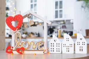 Schlüssel zu winzig Haus von gemütlich Zuhause mit Valentinstag Dekor auf Tabelle von Küche. Geschenk zum Valentinsgrüße Tag, Familie Liebe Nest. Design, Projekt, ziehen um zu Neu Haus, Hypothek, Miete und Kauf echt Nachlass foto