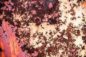 braune Grunge-Textur einer alten Metallwand mit Rost bedeckt. strukturierte Oberfläche mit interessantem Muster, schmutziges Blech mit abblätternder Farbe. verwitterte, raue und rostzerfressene Eisenwand der Garage. foto